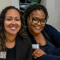 Two event attendees sitting together and smiling at camera